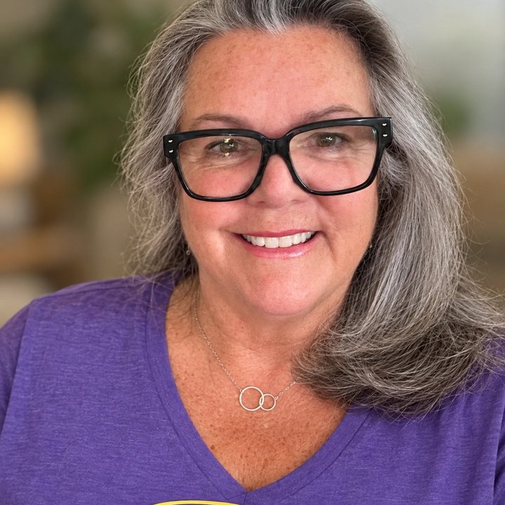 Natalie Flute, Vice President, smiling in dark-framed glasses and a purple top.