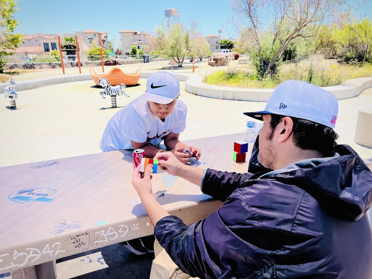 Two people playing chess at an outdoor table in a park.